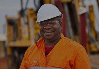 An image of a Kintyre employee smiling at the camera in orange coverlls and a white hardhat